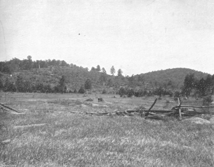 Black and white photograph of the two Round Tops, small hills next to each other in the distance, with flat land before them.