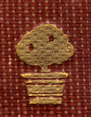 Decorated Adornment from the spine of the book, of a tree with gilt leaves on a burgundy woven ground.